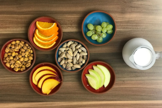 Top view of nuts in bowls, cut fruits.