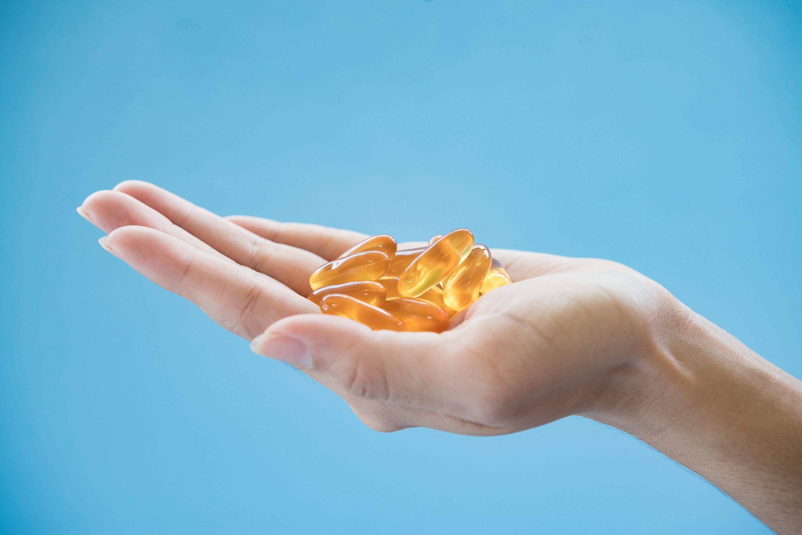 Omega-3 supplements in the palm of a hand.