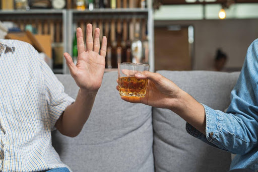 Hand saying no to alcohol in a glass