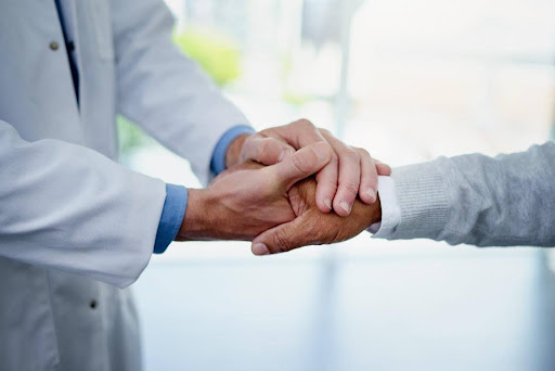 A doctor holding their patient's hand.