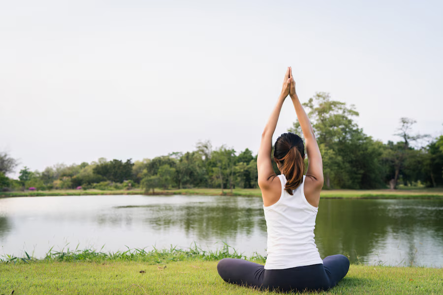 Posterior view of a woman practising yoga in the heart of nature.